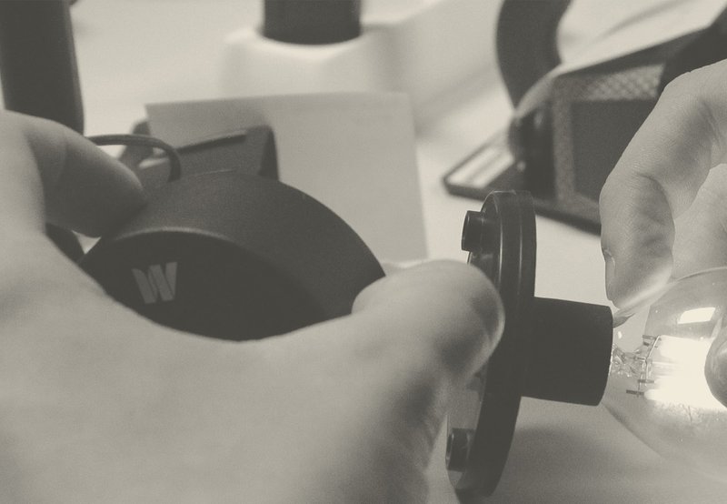 Mains en train de manipuler une lampe de la marque Watt&Home