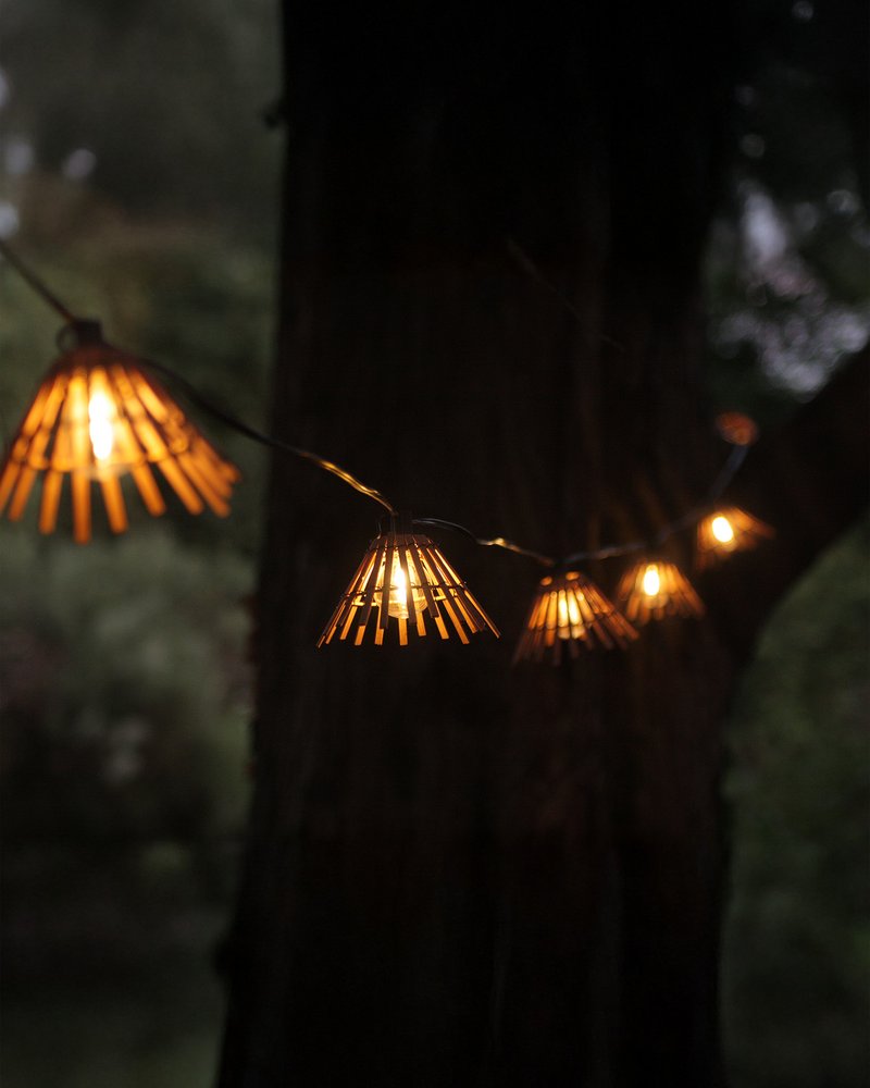 Guirlande en bois vue de nuit accrochée à un arbre.